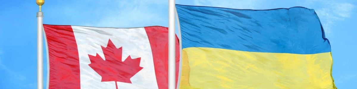 Canada and Ukraine two flags on flagpoles and blue cloudy sky background