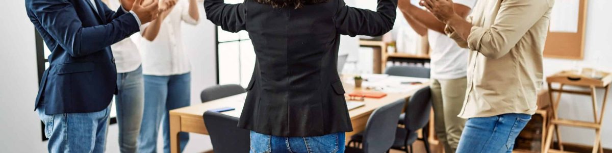 Group of young business workers smiling and clapping. Young businesswoman doing strong gesture with arms on back view at the office.