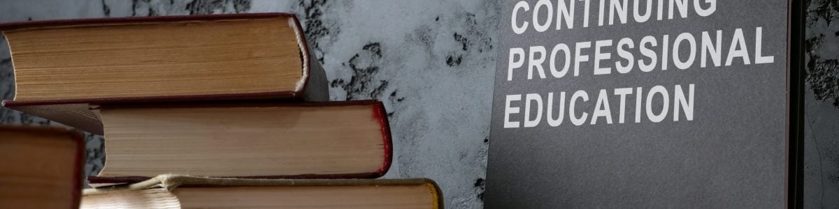 Continuing professional education on black notepad and books.