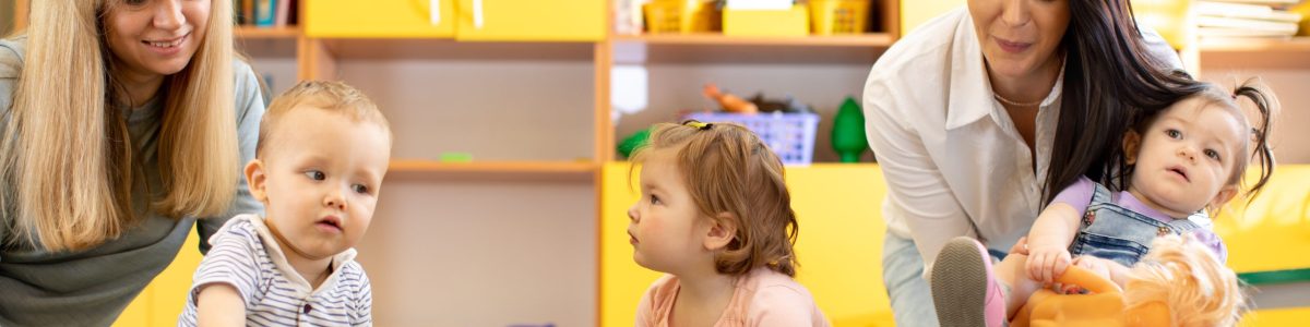 Nursery children playing with teacher and helper in kindergarten