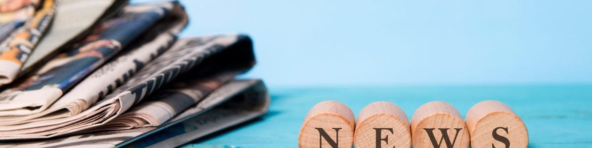 news word on wooden cube and newspapers