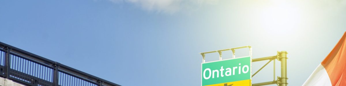 Destination province Ontario, Canada sign on highway with Canadian flag waving beside