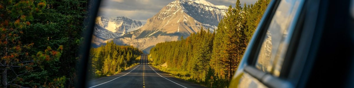 Driving a car through a mountain road that leads through the Canadian Rockies and watching the beautiful scenery in the rearview mirror in the icefields parkway, Jasper National Park, Alberta, Canada