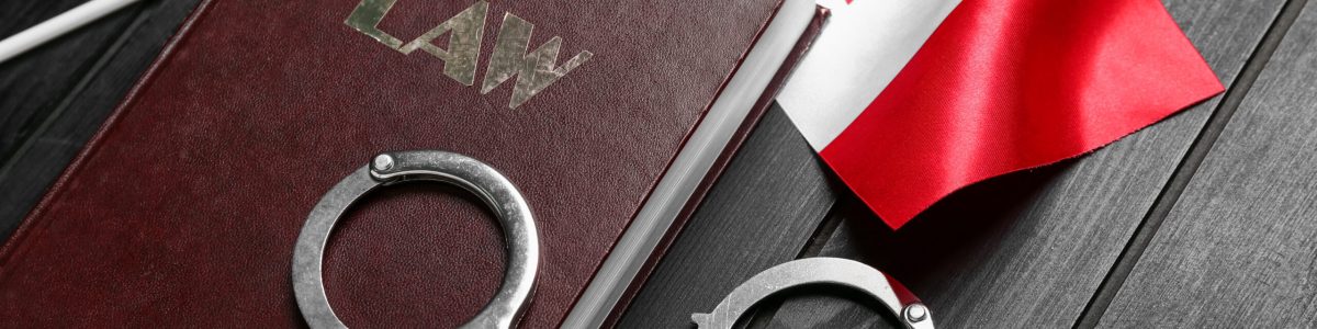 Canadian flag with law book and handcuffs on dark wooden background, closeup