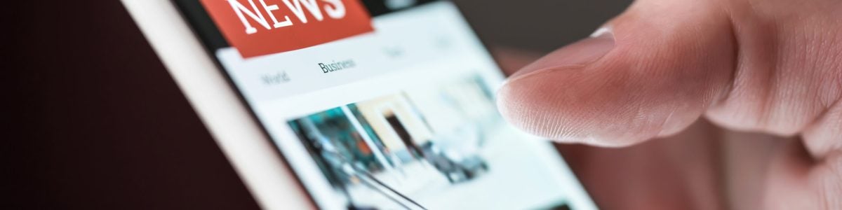 Mobile news application in smartphone. Man reading online news on website with cellphone. Person browsing latest articles on the internet. Light from phone screen.