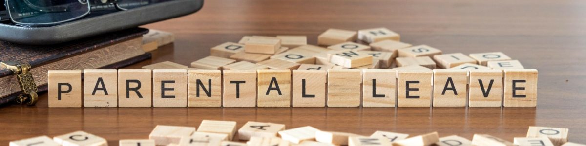 parental leave word or concept represented by wooden letter tiles on a wooden table with glasses and a book